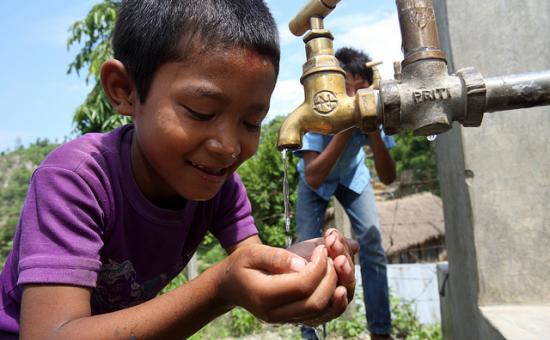 Boy drinks from a water tap in Nepal