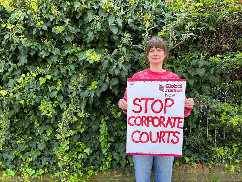 Activist holding a banner saying 'Stop corporate courts'