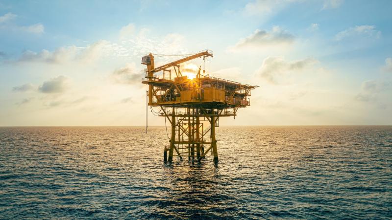 An oil rig in front of a setting sun