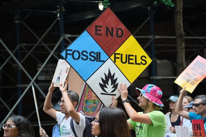 Protestor holding a banner saying 'End fossil fuels' during a climate march